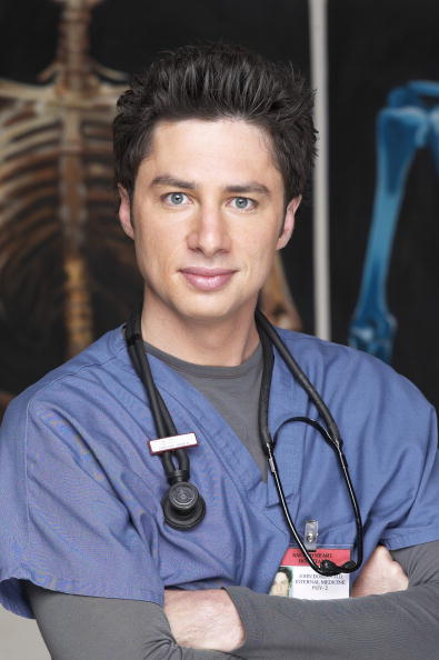 A headshot Zach Braff as JD on Scrubs. He is smiling while dressed in his doctor's uniform with a stethoscope around his neck